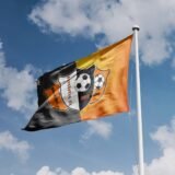 Flag on a pole with clouds behind.